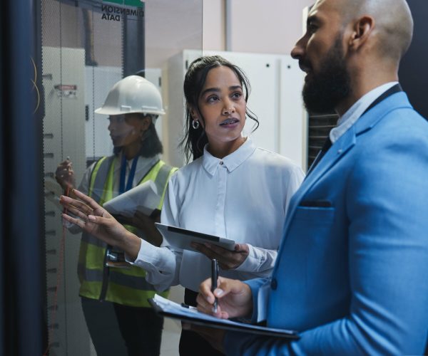Shot of two workers inspecting the electronic equipment in a server room together at work.