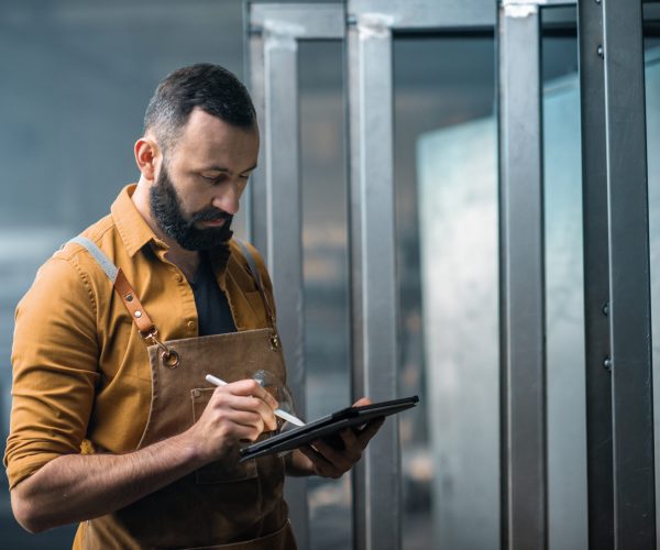 Engineer or factory worker using digital technology in the production of metal products, using a digital tablet at the plant. High quality photo